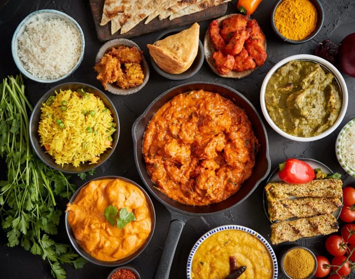 Various Indian dishes on a table. Spicy chicken Tikka Masala in iron pan. Served with rice, naan and spices. Set of different kind Indian food.